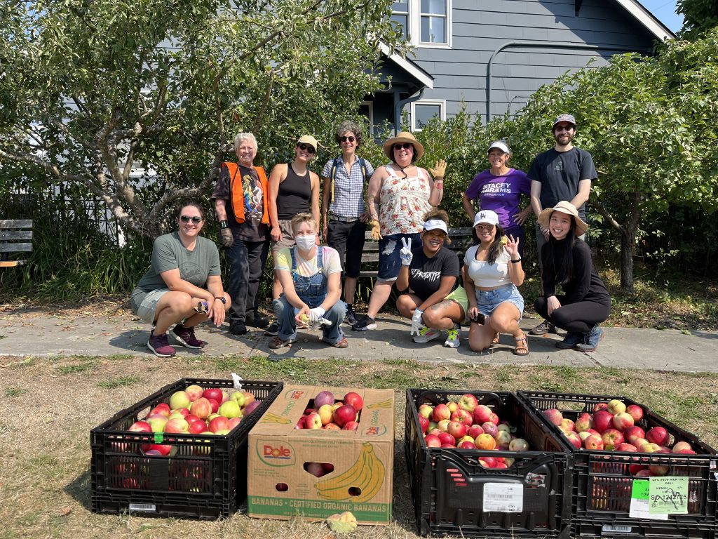 Image showing a grow of volunteers sitting and posing with a few crates of recently harvested apples.